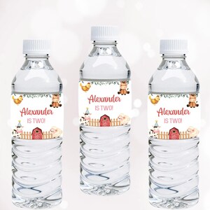 Könnte beinhalten: Drei transparente Wasserflaschen mit weißen Verschlüssen. Jede Flasche hat ein Etikett mit dem Namen "Alexander" und dem Text "IS TWO!" in Rot. Die Etiketten zeigen Illustrationen von Hoftieren, darunter eine Kuh, ein Schaf, ein Pferd und ein Huhn, sowie eine rote Scheune.