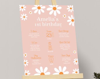 Könnte beinhalten: Ein rosa-weißes Meilenstein-Poster zum ersten Geburtstag mit Gänseblümchen. Das Poster enthält Informationen über das Kind, wie Alter, Größe, Gewicht, Lieblingsessen, Lieder und Spielzeug. Der Text lautet "Amelia's 1st birthday".