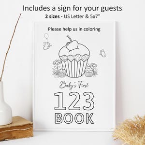 May include: A black and white printable sign for a baby's first book. The sign features a cupcake with a cherry on top and the text "Baby's First 123 BOOK".