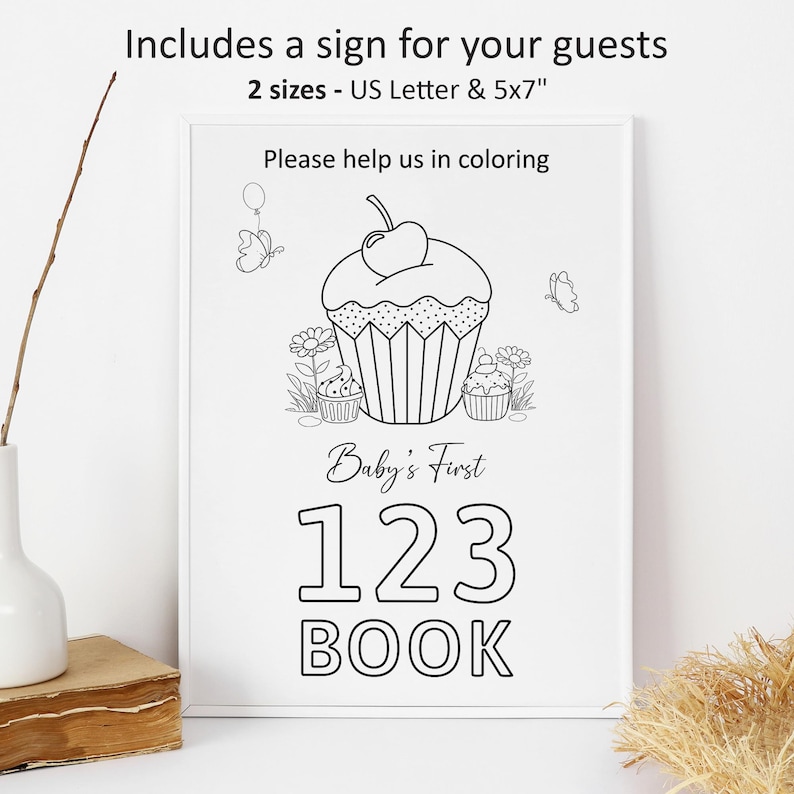 May include: A black and white printable sign for a baby's first book. The sign features a cupcake with a cherry on top and the text "Baby's First 123 BOOK".