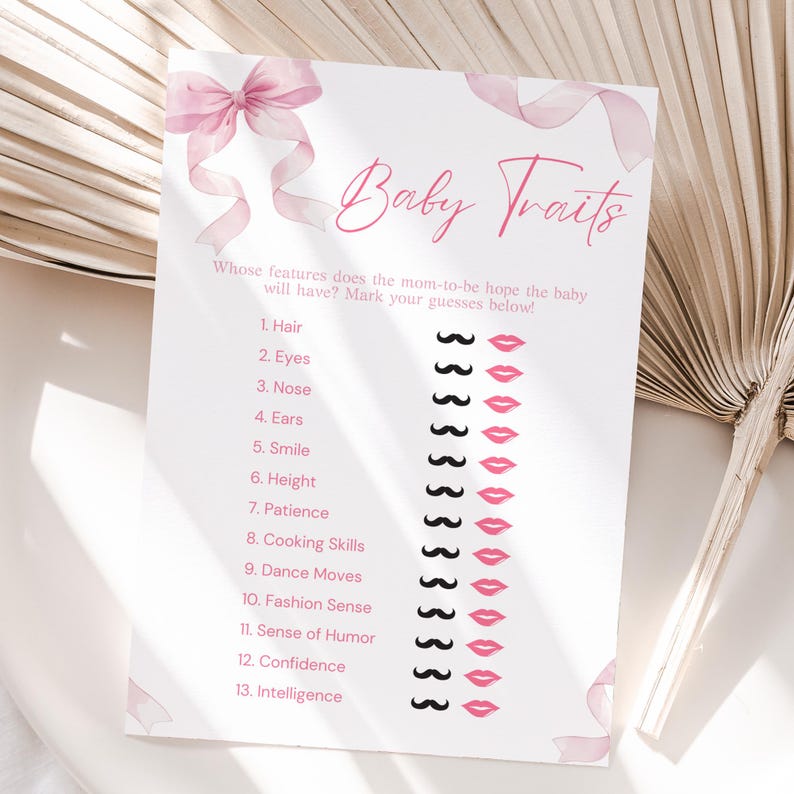 May include: A baby shower game card with the title "Baby Traits" in pink script. The card features a list of traits with mustache and lip graphics for marking guesses. A pink bow and ribbon design adorns the top.
