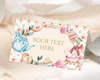 May include: A whimsical Alice in Wonderland themed place card with a teacup, teapot, and a mouse wearing a hat. The card is decorated with flowers, hearts, and a gold frame. The text "YOUR TEXT HERE" is printed on the card.