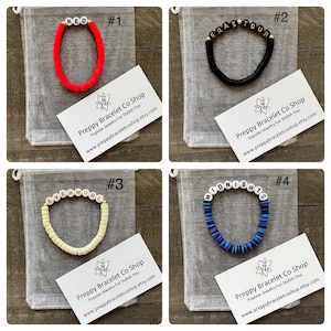 K&ouml;nnte beinhalten: Vier bunte Armb&auml;nder mit wei&szlig;en Buchstabenperlen, die "RED", "ERAS TOUR", "EVERMORE" und "MIDNIGHTS" buchstabieren. Jedes Armband wird in einem wei&szlig;en Organzas&auml;ckchen mit einer Visitenkarte pr&auml;sentiert, auf der "Preppy Bracelet Co Shop" steht und die Website-Adresse angegeben ist.