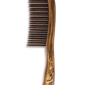 May include: A wooden comb with a curved handle and fine teeth. The comb is made of dark brown wood with a natural grain pattern. The handle is decorated with a gold floral design.
