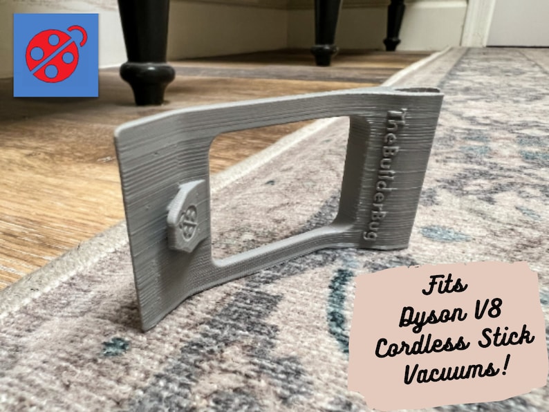 May include: Gray 3D printed wall mount for a Dyson V8 cordless stick vacuum. The mount has a rectangular opening and the text "The Builder Bug" is printed on the side.