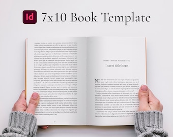 Op de afbeelding: Een 7x10 boektemplate-mockup met een witte achtergrond. Het boek is open en de tekst "INSERT CHAPTER NUMBER HERE" en "Insert title here" is zichtbaar op de rechterpagina. Het boek wordt vastgehouden door een persoon die een grijze trui draagt.