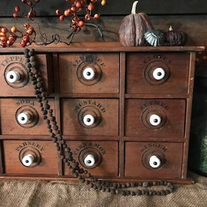 May include: A wooden spice rack with 9 drawers, each with a white knob and a black label. The labels read "Pepper", "Allspice", "Cloves", "Soda", "Mustard", "Nutmeg", "Parsley", "Cinnamon", and "Ginger".