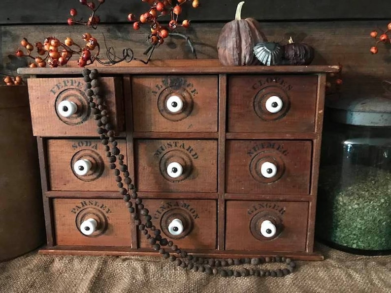 May include: A wooden spice rack with 9 drawers, each with a white knob and a black label. The labels read "Pepper", "Allspice", "Cloves", "Soda", "Mustard", "Nutmeg", "Parsley", "Cinnamon", and "Ginger".