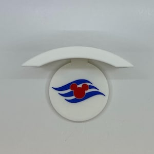 May include: A white, circular emblem featuring a red Mickey Mouse head and blue wave designs. Above the emblem is a white, curved, semi-circular piece. The design is reminiscent of a cruise ship logo.