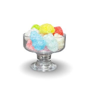 May include: A glass bowl filled with colorful candy. The candy is in the shape of small, irregular balls and is a mix of pink, blue, yellow, and white.
