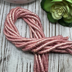 May include: A strand of pink metallic disc beads. The beads are about 1/2 inch in diameter and have a shiny finish.