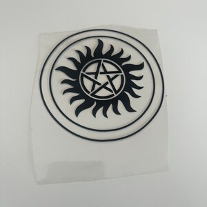 Pu&ograve; includere: Adesivo circolare nero con un design a raggiera stilizzato e una stella a cinque punte al centro. L'adesivo &egrave; su un supporto trasparente. Un elemento grafico audace.