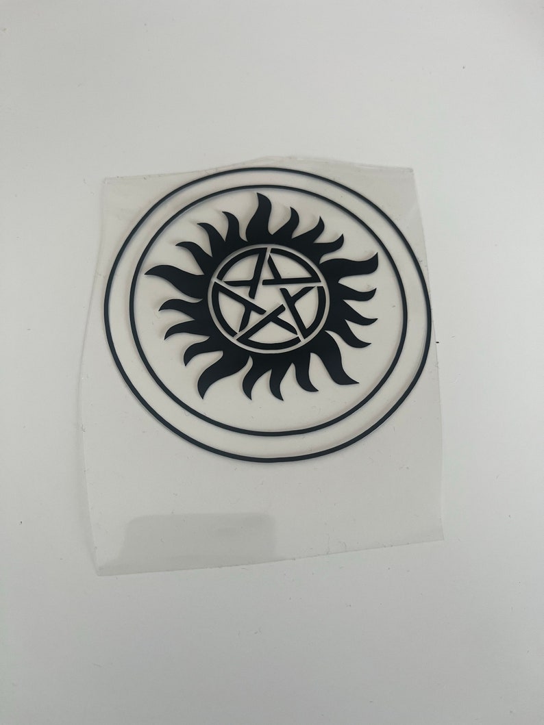 Pu&ograve; includere: Adesivo circolare nero con un design a raggiera stilizzato e una stella a cinque punte al centro. L'adesivo &egrave; su un supporto trasparente. Un elemento grafico audace.