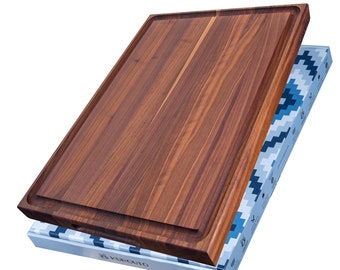 May include: A rectangular wooden cutting board with a juice groove, displayed on its packaging. The board is a rich brown color with visible wood grain. The packaging is white with a blue and white geometric pattern and the brand name "KUROUTO".
