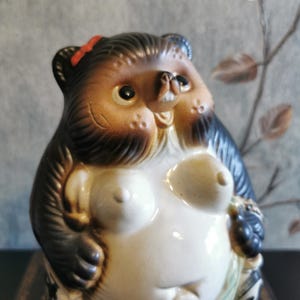 Può includere: Una tazza di ceramica bianca con manico nero e la scritta "But First, Coffee" in nero, in grassetto. La tazza è appoggiata su una superficie bianca. La tazza è alta circa 10 cm.