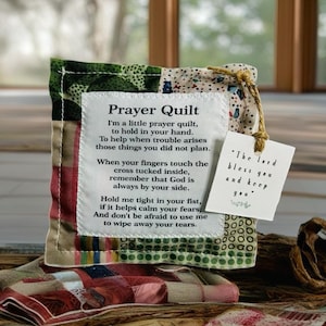 Può includere: Una piccola trapunta da preghiera patchwork con un'etichetta bianca che recita "Prayer Quilt" e una poesia sull'uso della trapunta per il conforto e la preghiera. L'etichetta include anche il testo "The Lord bless you and keep you".