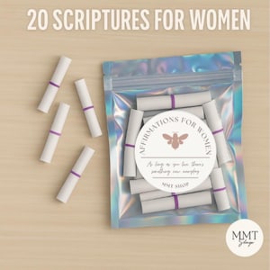 May include: A clear plastic bag filled with rolled white paper scrolls, each secured with a purple band. The bag has a label that reads "AFFIRMATIONS FOR WOMEN" with a bee graphic. The text "20 SCRIPTURES FOR WOMEN" is at the top.