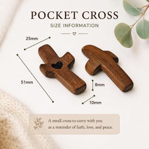 May include: Two dark brown wooden pocket crosses with smooth surfaces. One cross features a small black heart engraving. Text reads POCKET CROSS SIZE INFORMATION and A small cross to carry with you as a reminder of faith, love, and peace. Dimensions are 51mm by 25mm by 10mm by 8mm.
