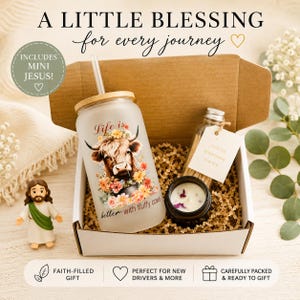 May include: A gift box containing a frosted glass tumbler with a straw, featuring a highland cow and floral graphic with the text Life is better with fluffy cows, a small candle, a jar of matches, and a miniature Jesus figurine.