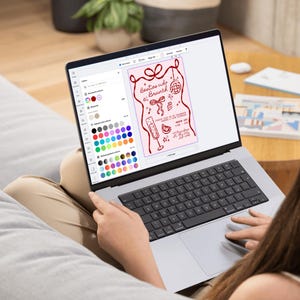 May include: A laptop screen showing a design for "Besties who Brunch" with a pink background and red illustrations. The design includes a bow, disco ball, champagne flute, and other brunch-related graphics. The laptop is open on a person's lap.