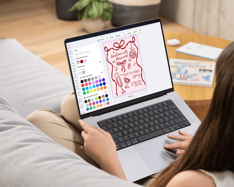 May include: A laptop screen showing a design for "Besties who Brunch" with a pink background and red illustrations. The design includes a bow, disco ball, champagne flute, and other brunch-related graphics. The laptop is open on a person's lap.