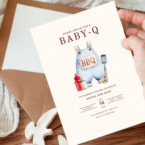 May include: A baby shower invitation with a BBQ theme. The invitation features a watercolor illustration of blue gingham overalls with the word "BBQ" on them. The text reads "Please join us for a Baby-Q" and includes the date, time, and location.