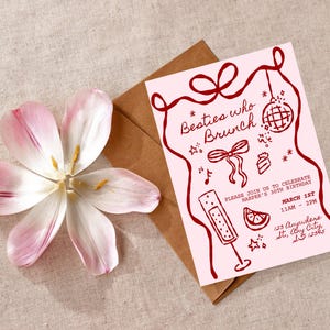 May include: A pink invitation with the text "Besties who Brunch" and red illustrations. A brown envelope and a pink and white flower are also in the image.