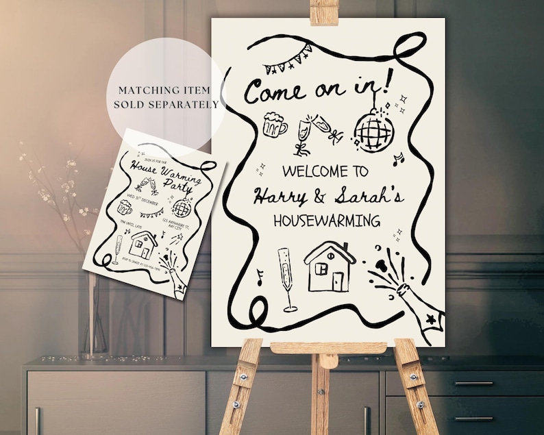 May include: A cream-colored housewarming party sign on a wooden easel. The sign reads "Come on in! Welcome to Harry & Sarah's Housewarming" with decorative illustrations. A smaller matching card is also visible.