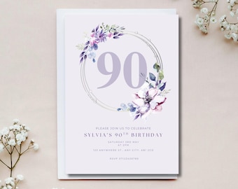 May include: A 90th birthday invitation card with a floral wreath design. The card features the number 90 in a large, soft purple font, surrounded by a silver frame and a wreath of purple and white flowers. The text reads "Please join us to celebrate Sylvia's 90th birthday."