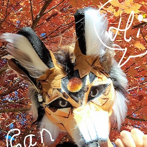 welcome this is lunar Forest. Lunar is the type of moon the center of his forehead. it has beautifully blended yellow, orange, and reds. This glowing moon holds the spirit of the coyote who can be found out in the wild beneath the full moon. You can see his designs are similar to the original Forest but his eyes set him apart as well. They are a black tightly woven eye mesh with realistic silver pupils. He has the same bark like ear tuffs, fluffy fur, and wood like patterns on his famous face.