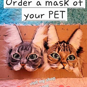 May include: Two cat masks with realistic features, including detailed fur and expressive eyes. The masks are made of cardboard and are designed to resemble a cat's face. Text on the image reads "Order a mask of your PET" and "visit my shop page +30 mask designs."