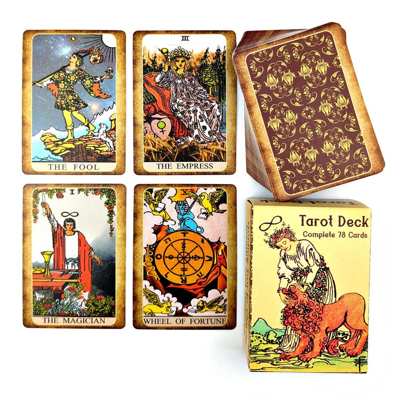 Może przedstawiać: Talia kart tarota w ż&oacute;łtym i brązowym pudełku przedstawiającym kobietę i lwa. Pudełko zawiera napis "Tarot Deck Complete 78 Cards". Karty są ilustrowane kolorowymi obrazkami i zawierają karty: Głupiec, Cesarzowa, Mag i Koło Fortuny.