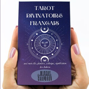 May include: A tarot card deck with a dark blue cover featuring white text that reads "TAROT DIVINATOIRE FRANGAIS". The design includes a sun, crescent moons, and a circular pattern. The bottom of the deck has the text "WITCHY CAUMORON".