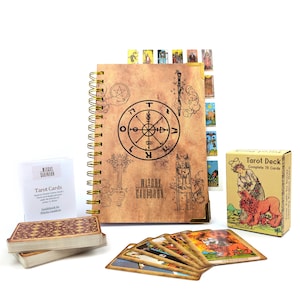 May include: A tarot card set with a spiral-bound journal, a deck of cards, and a box. The journal has a brown cover with a wheel design and the text "Witchy Cauldron". The box is tan with a woman and lion illustration.