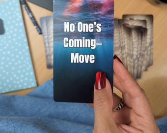 May include: A rectangular card with the text "No One's Coming - Move" against a backdrop of an underwater scene with a red and blue sky. The card is held in a hand with red nail polish, with other cards and a notebook in the background.