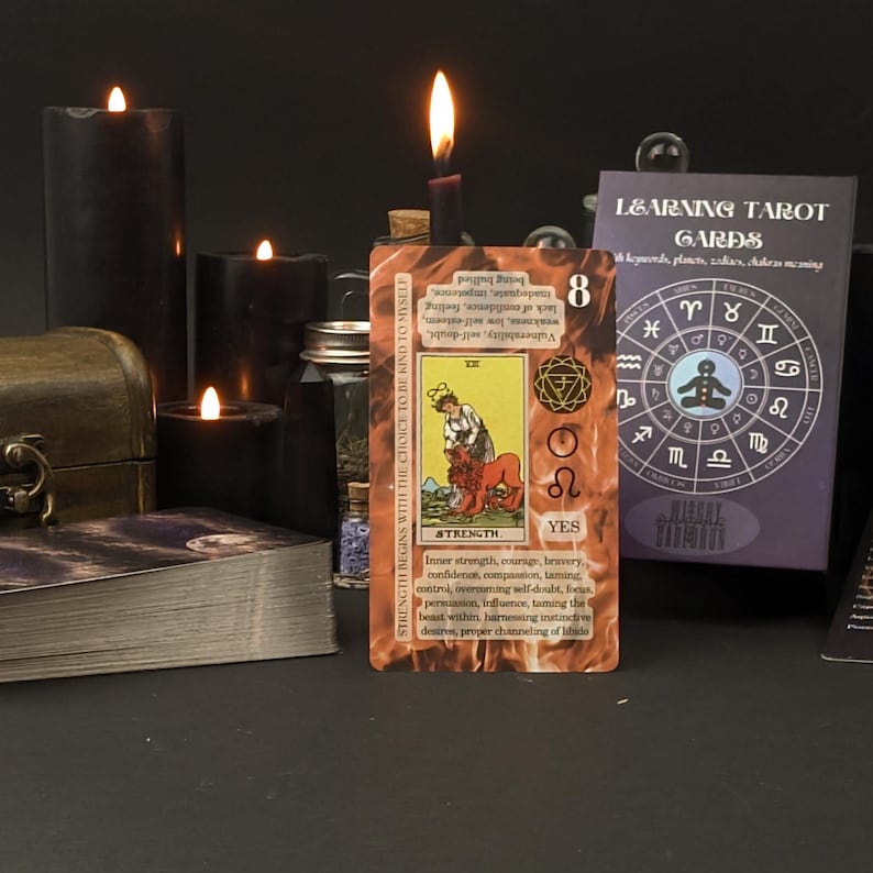 May include: A tarot card showing the Strength card, with a woman and lion illustration, illuminated by a candle. Other candles, a deck of cards, and a box are in the background. The card reads "Strength".