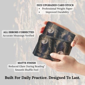 May include: A deck of tarot cards with a matte finish, featuring a celestial design with a moon and stars. The cards are held in a person's hands. Text on the cards reads "2023 Upgraded Card Stock" and "Built For Daily Practice. Designed To Last."