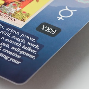 May include: A tarot card with the word "MAGICIAN" and the word "YES" in a black box. The card has a blue background and features additional text including words like "action, power, skill, magic, work."