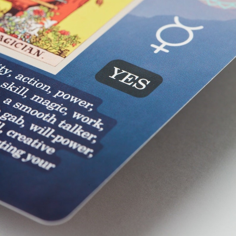 May include: A tarot card with the word "MAGICIAN" and the word "YES" in a black box. The card has a blue background and features additional text including words like "action, power, skill, magic, work."