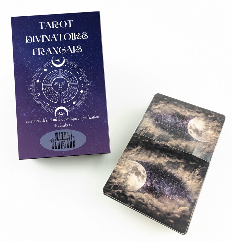 May include: A tarot card deck and box set. The box is dark purple with white text that reads "TAROT DIVINATOIRE FRANGAIS". The box has a celestial design with a sun, moon, and stars. The cards have a night sky and moon design.