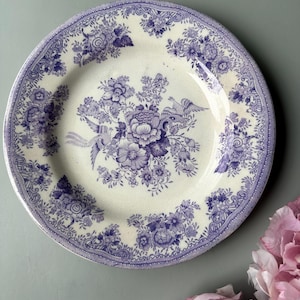 Peut inclure: Une assiette en céramique blanche avec un motif floral bleu et blanc. L'assiette a un bord festonné et un rebord surélevé. Le motif floral comprend des oiseaux et des fleurs.