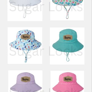 May include: Set of five sun hats with different patterns and colors. Each hat has a brown patch with the word "Name" written in black. The hats are white, pink, light blue, purple, and a floral pattern.