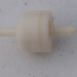 Op de afbeelding: Witte plastic brandstoffilter met twee kleine buizen aan beide uiteinden.