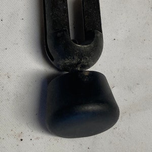 Könnte beinhalten: Schwarzer Kunststoff-Stuhlbeinersatz mit U-förmiger Oberseite und rundem Boden.