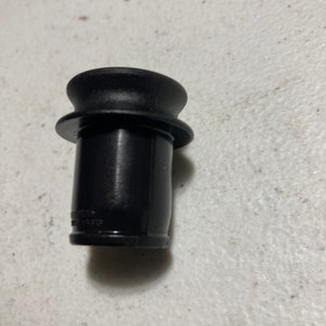May include: Black plastic bottle stopper with a flared top and a smooth, cylindrical body.