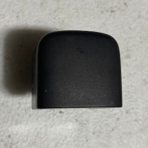 May include: A black plastic door handle with a rounded top and a textured surface.