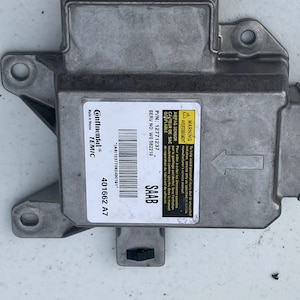 May include: A gray metal car part with a yellow warning label that reads "WARNING AMPAG SENSOR CATEUR DE SAC GONFLABLE P/N: 1277 1237 SERV NO: WO 582219 SAAB" and the text "Continental TEMIC 401662 A7".