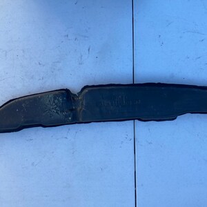 Pode incluir: Uma tira de para-choques de borracha preta com uma ligeira curva no meio. A tira está ligeiramente gasta e tem algumas pequenas rachaduras.