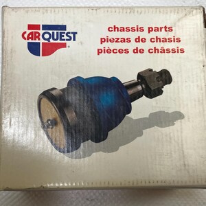 Puede incluir: Una pieza de chasis nueva, probablemente una rótula, se muestra en su caja original. La caja presenta el logotipo "CAR QUEST" y texto en inglés, español y francés. La rótula tiene una bota de goma azul y un cuerpo metálico.