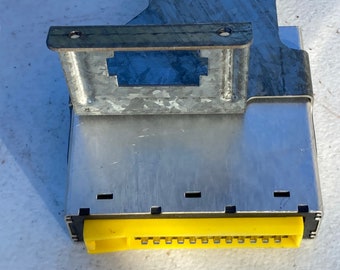 May include: A silver metal electrical component with a yellow connector. The component has a rectangular shape and a metal bracket on the top.